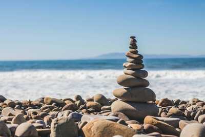 Rochers en équilibre au premier plan, plage à l'arrière-plan