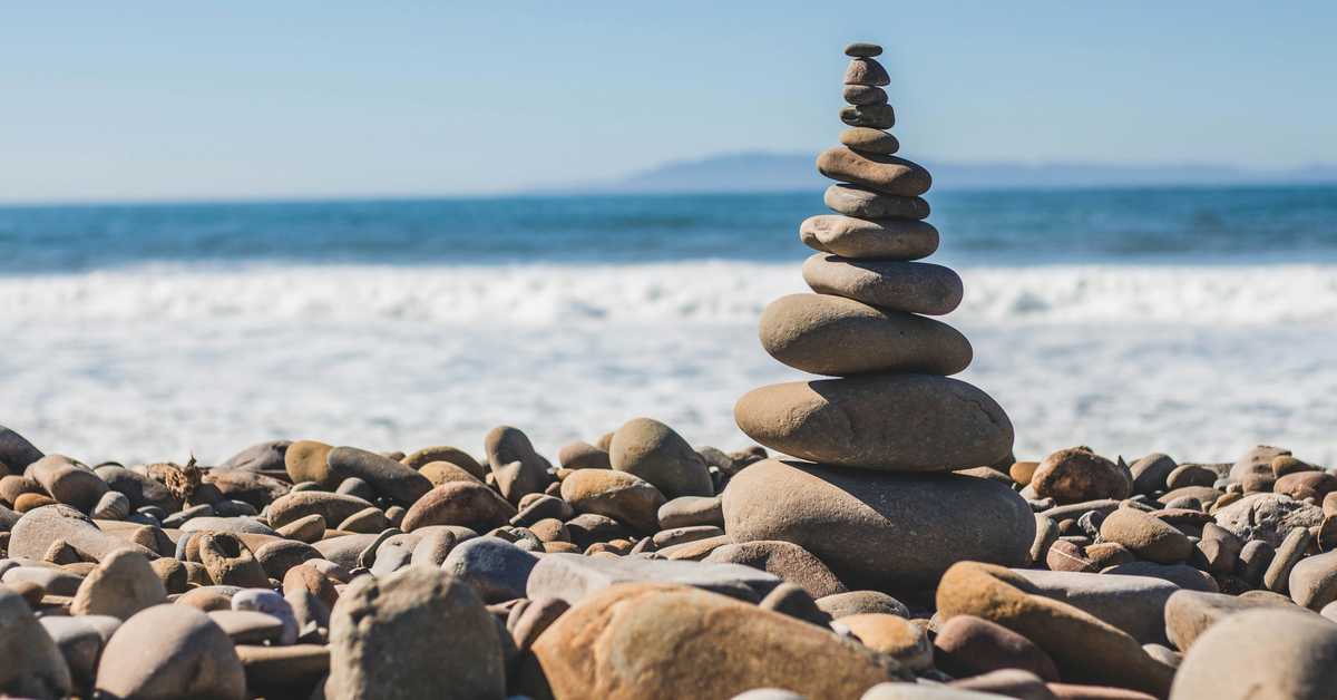 Rochers en équilibre au premier plan, plage à l'arrière-plan